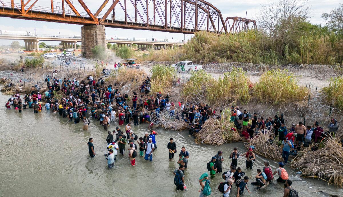 Illegal immigrants wait in the Rio Grande for an opening in the razor wire barrier to cross into the United States in Eagle Pass, Texas, on Sept. 25, 2023. (Andrew Caballero-Reynolds/AFP via Getty Images)
