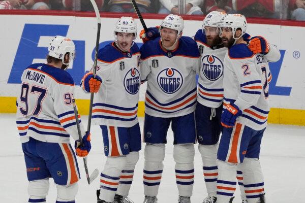 Edmonton Oilers players surround right wing Corey Perry (90) after he scored a goal during the second period of Game 5 of the Stanley Cup Finals against the Florida Panthers, in Sunrise, Fla., on June 18, 2024, (AP Photo/Rebecca Blackwell)