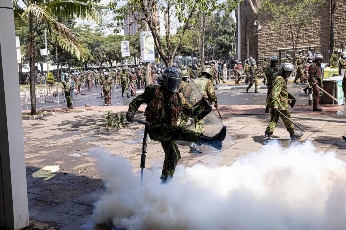 A Kenyan police officer wearing riot gear kicks a tear gas canister during a protest against the finance bill in Nairobi, Kenya, on June 25, 2024. (Patrick Meinhardt/Getty Images)