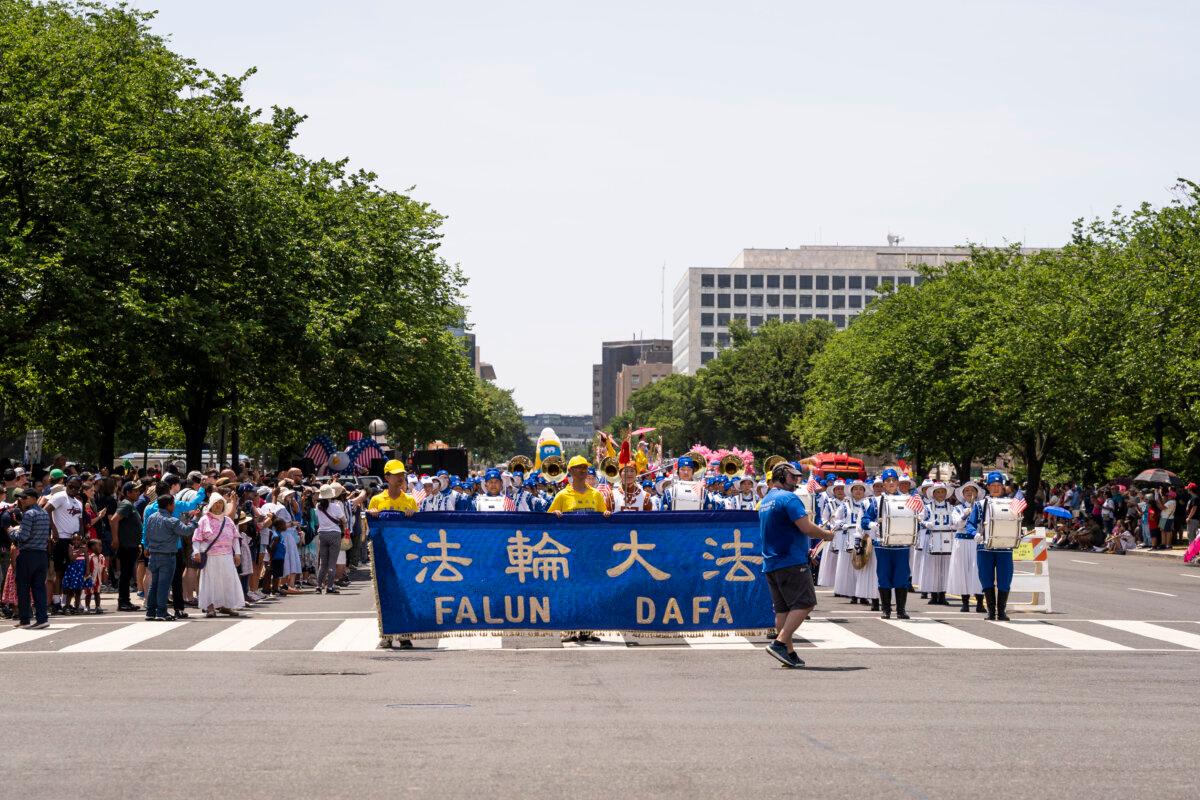 Falun Gong practitioners, followed by the Tian Guo Marching Band, during the National Independence Day parade in Washington on July 4, 2024. (Caroline Li/The Epoch Times)