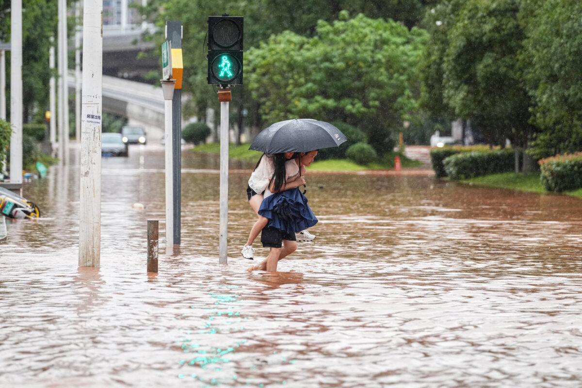 People wade through a flooded street following heavy rains in Changsha, in central China's Hunan province on June 24, 2024. (STR/AFP via Getty Images)