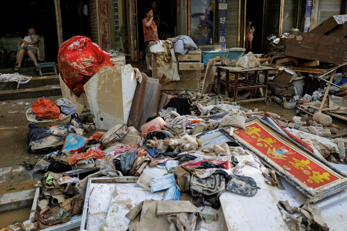 Residents look on near a pile of debris after a flood following heavy rainfall in Pingjiang county of Yueyang, Hunan province, on July 3, 2024. (Tingshu Wang/Reuters)