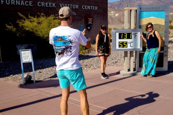 Matt Fiedler takes a photo of daughter Sally Fiedler (L), and wife Cecilia Fiedler by the thermometer at the Furnace Creek Visitor Center in Death Valley, Calif., on July 9, 2024. (Ty Oneil/AP Photo)