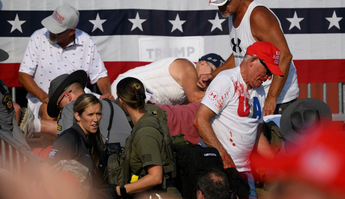 Audience members duck in the crowd during a shooting at a campaign rally for former President Donald Trump in Butler, Pa., on July 13, 2024. The Butler County District Attorney said the suspected gunman is dead after injuring former President Trump, killing one audience member, and seriously injuring two others. (Jeff Swensen/Getty Images)