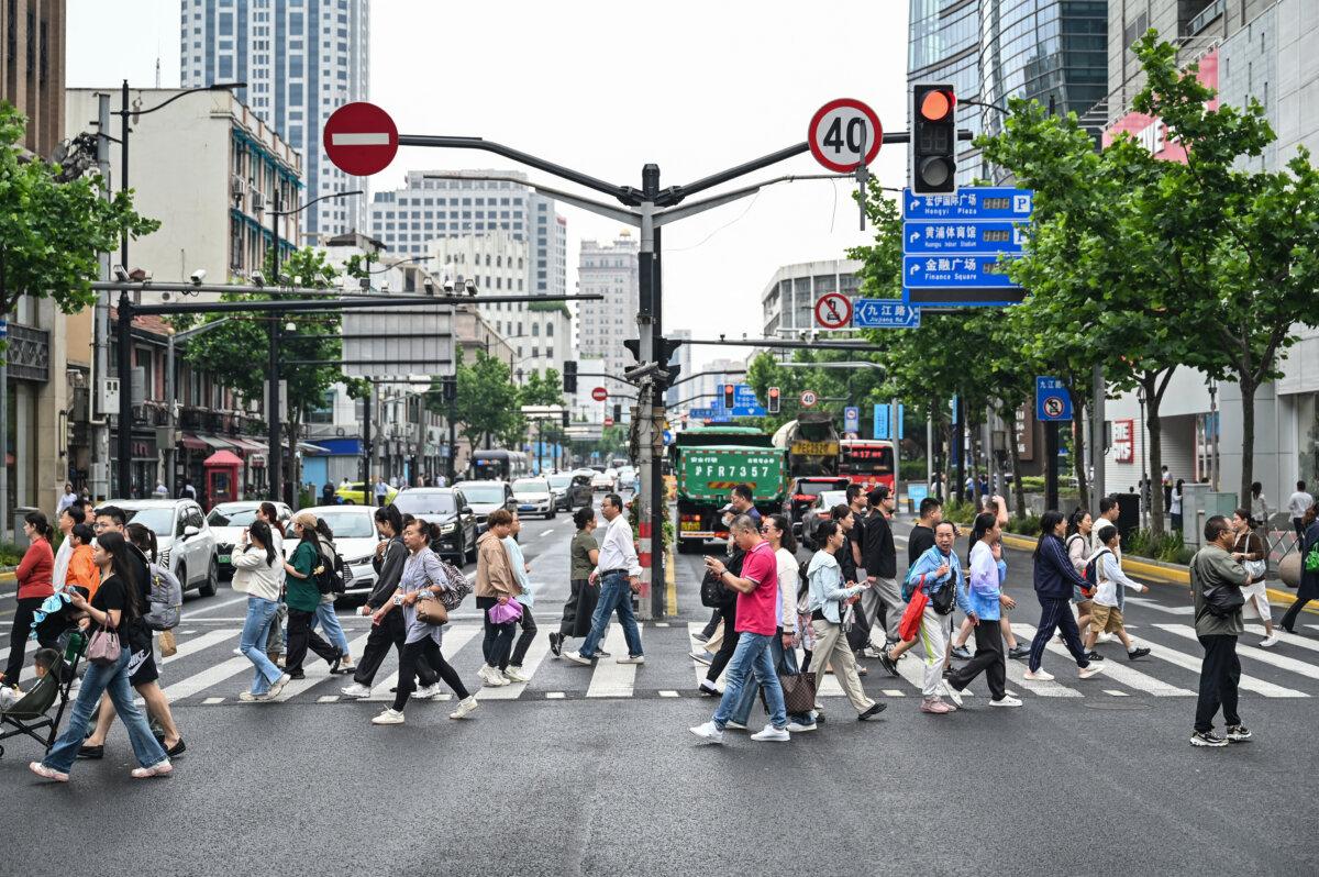 People cross a street in the Huangpu District in Shanghai on June 6, 2024. (Hector Retamal/AFP via Getty Images)