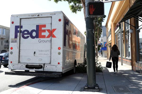 A pedestrian walks by a parked FedEx delivery truck in San Francisco, Calif., on March 21, 2024. (Justin Sullivan/Getty Images)