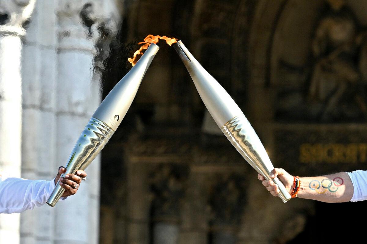 Claudia Tagbo, French-Ivorian actress and comedian, and Pascal Touitou carry the Olympic Torch at Basilique du Sacre-Coeur de Montmartre during the second day of the Paris 2024 Olympic Torch Relay in Paris, France, on July 15, 2024. (Kristy Sparow/Getty Images)
