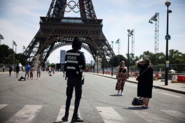 A security officer watches people take photographs in front of the Eiffel Tower at the 2024 Summer Olympics, in Paris, France, on July 20, 2024. (Thomas Padilla/AP Photo)