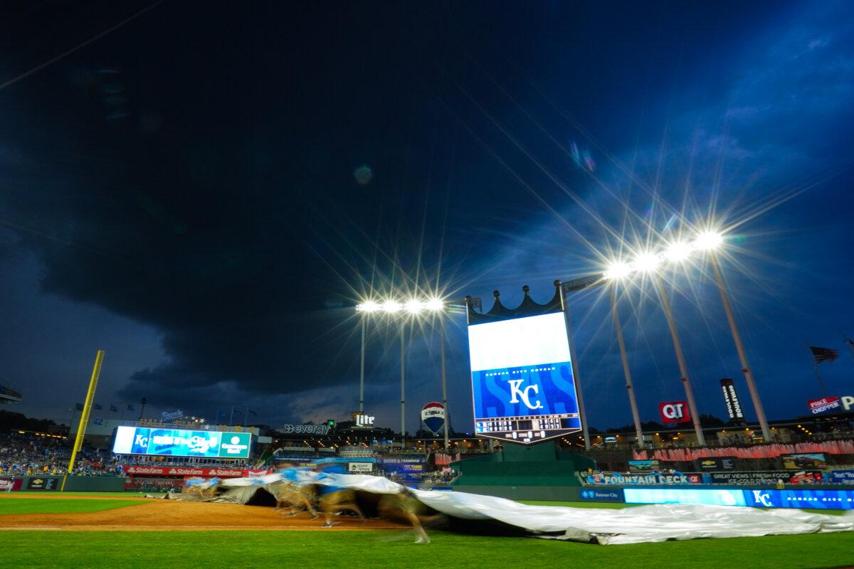 Groundskeepers begin to roll out a tarp as a storm causes a rain delay during the sixth inning of the game between the Kansas City Royals and the Tampa Bay Rays at Kauffman Stadium in Kansas City, Mo., on July 2, 2024. (Kyle Rivas/Getty Images)