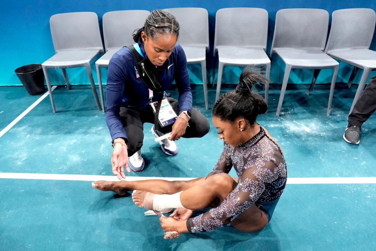 Simone Biles of the United States has her ankle taped after competing on the uneven bars during a women's artistic gymnastics qualification round at Bercy Arena at the 2024 Summer Olympics in Paris, France, on July 28, 2024. (Charlie Riedel/AP Photo)