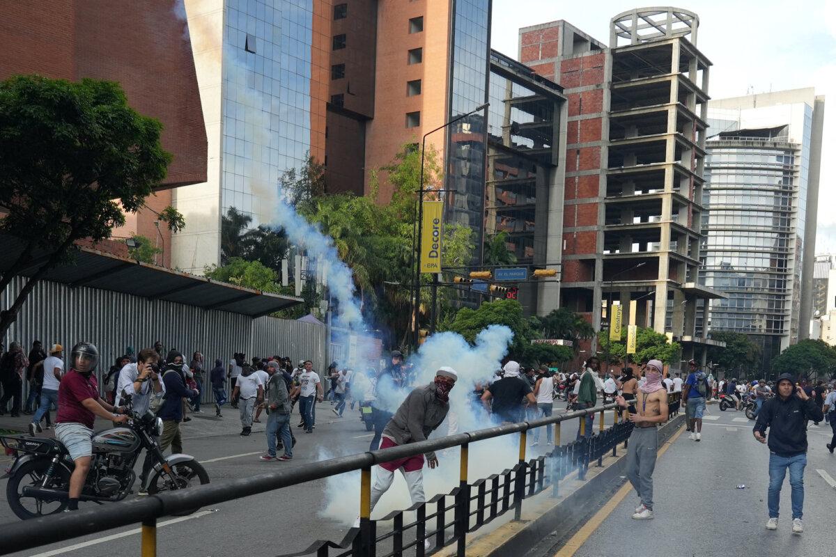A protester throws back a tear gas canister as Venezuelan opposition supporters protest following the announcement by the National Electoral Council that Venezuela's President Nicolas Maduro won the presidential election, in Caracas, Venezuela, on July 29, 2024. (Alexandre Meneghini/Reuters)