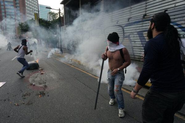 Protesters run to take cover from tear gas as Venezuelan opposition supporters protest in Caracas, Venezuela, on July 29, 2024. (Alexandre Meneghini/Reuters)