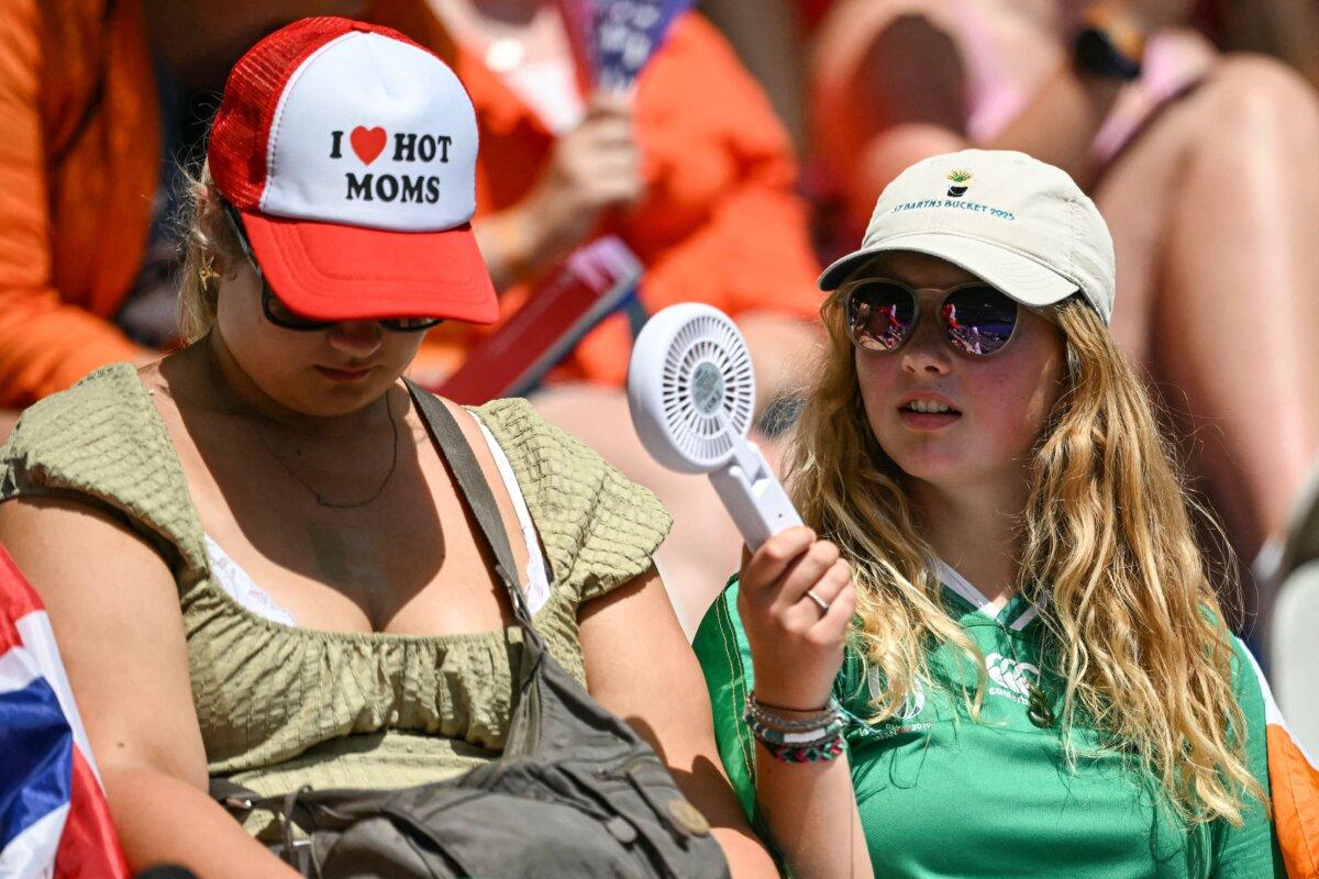 Fans use a fan to fight the heat as they arrive to attend the women's rugby sevens matches during the Paris 2024 Olympic Games at the Stade de France in Saint-Denis on July 30, 2024. (Carl De Souza/ AFP via Getty Images)