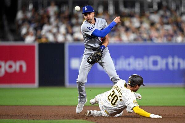 Nick Ahmed (12) of the Los Angeles Dodgers throws to first base after forcing out Kyle Higashioka (20) of the San Diego Padres at second base to complete a double play during the fifth inning in San Diego on July 30, 2024. (Orlando Ramirez/Getty Images)