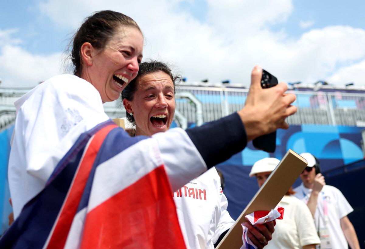 Gold medalists Emily Craig and Imogen Grant of Team Great Britain talk with their families on mobile phones after the Rowing Lightweight Women's Double Sculls medal ceremony on day seven of the Olympic Games Paris 2024 at Vaires-Sur-Marne Nautical Stadium in Paris on August 2, 2024. (Alex Davidson/Getty Images)