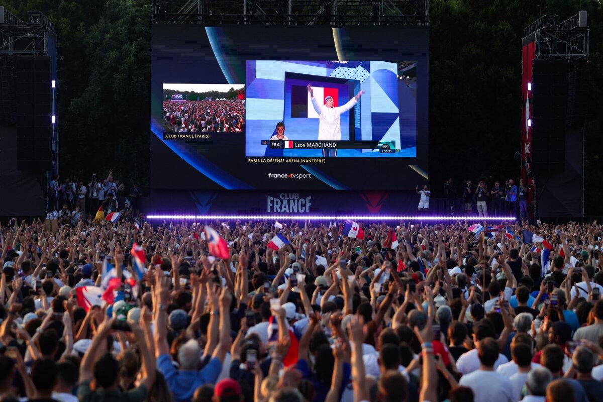 Supporters cheers as they watch on a giant screen France's Leon Marchand arriving for the final of the men's 200m individual medley swimming event during the Paris 2024 Olympic Games at the "Club France" in the Nations parc in Paris on August 2, 2024. (Thibaud Moritz/AFP via Getty Images)