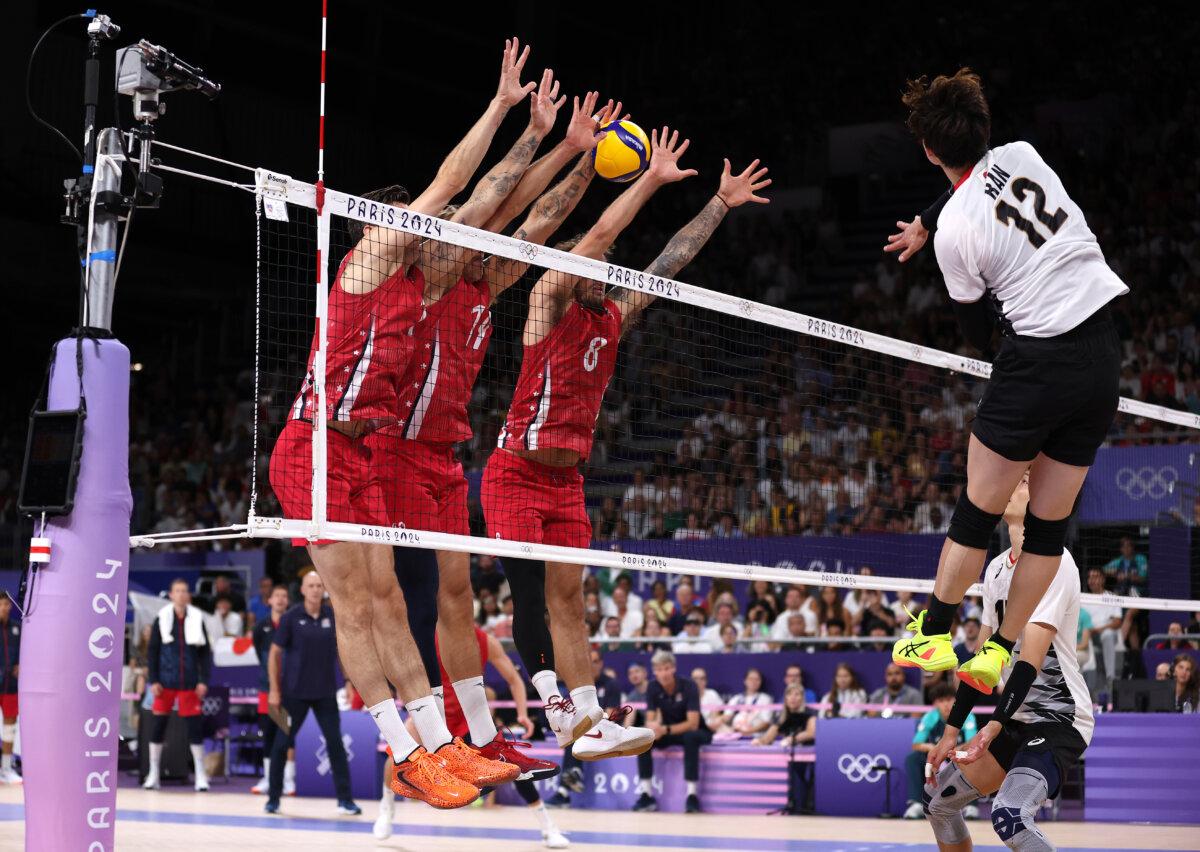 Ran Takahashi #12 of Team Japan attacks the net against Micah Christenson #11 and Torey Defalco #8 of Team United States during the Men's Preliminary Round - Pool A match between Team France and Team Slovenia on day seven of the Olympic Games Paris 2024 at Paris Arena on August 02, 2024 in Paris, France. (Photo by Ezra Shaw/Getty Images)