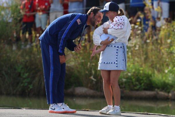 Gold medallist US' Scottie Scheffler celebrates with his wife Meredith Scudder and their child during the podium ceremony after round 4 of the men’s golf individual stroke play of the Paris 2024 Olympic Games in Paris on Aug. 4, 2024. (Emmanuel Dunand/AFP)
