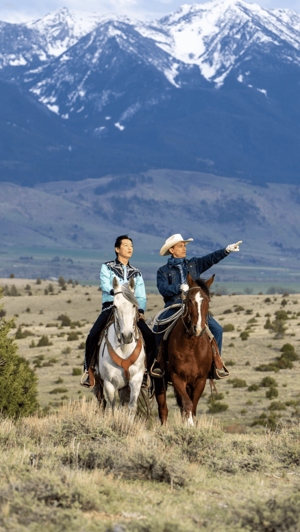 Javier (Goya Robles, R) offers Hideki (Arata Iura) his old rodeo-riding threads, and takes him on a tour of the ranch, in "Tokyo Cowboy." (Salaryman Films LLC)