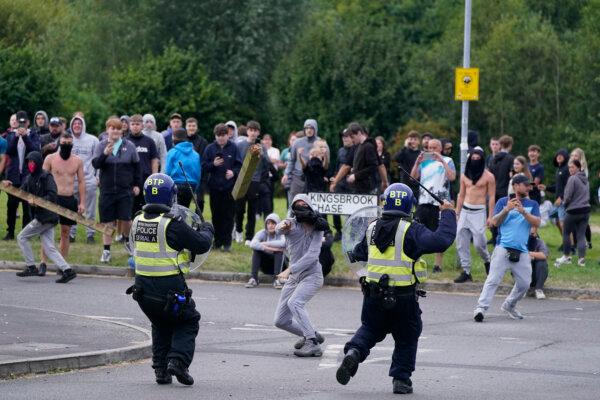 A youth throws a fence post towards police during an anti-immigration demonstration near the Holiday Inn Express in Rotherham, England, on Aug. 4, 2024. (Danny Lawson/PA Wire)