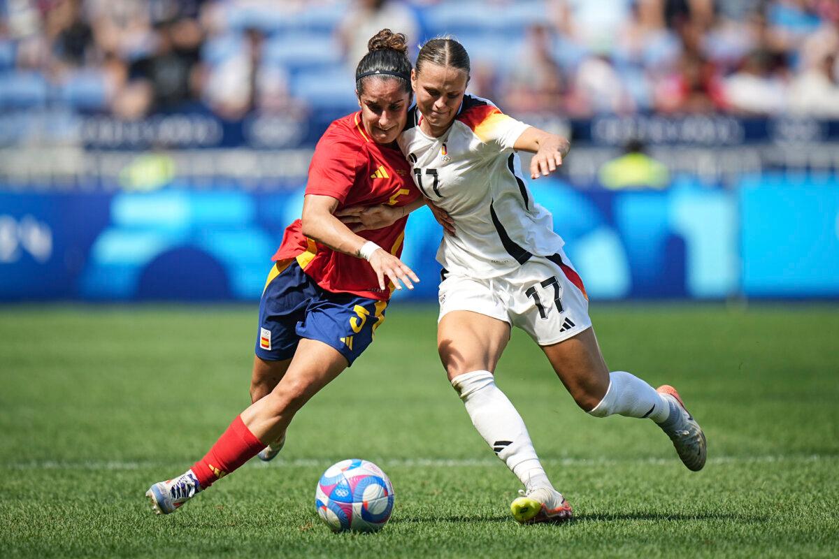 Spain's Oihane Hernandez (L) challenges for the ball with Germany's Klara Buehl during the women's bronze medal soccer match between Spain and Germany during the 2024 Summer Olympics at the Lyon stadium in Decines, France, on Aug. 9, 2024. (Laurent Cipriani/AP Photo)