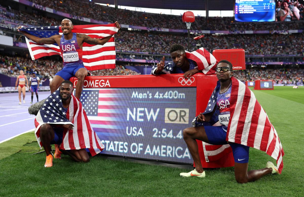 Gold medalists and new Olympic record holders Christopher Bailey, Vernon Norwood, Bryce Deadmon, and Rai Benjamin of Team United States pose for a photo in front of the scoreboard following the men's 4 x 400m relay final on day 15 of the Olympic Games at Stade de France in Paris on Aug. 10, 2024 (Patrick Smith/Getty Images)