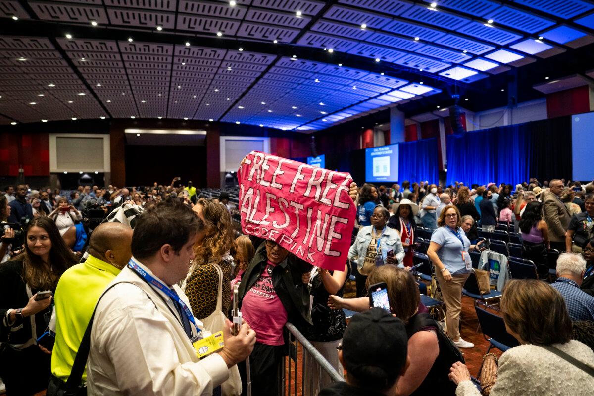 Protestors shout while Democratic Vice President Minnesota Gov. Tim Walz speaks at the women’s caucus at Hyatt Regency McCormick Place on the second day of the Democratic National Convention in Chicago on Aug. 20, 2024. (Madalina Vasiliu/The Epoch Times)
