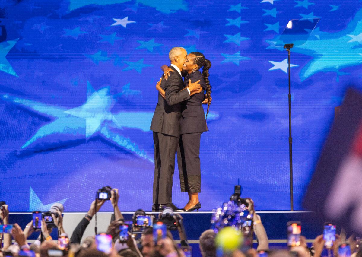 Barack and Michelle Obama hug on stage at night two of the 2024 DNC held in Chicago, Ill., on Aug. 20, 2024. (John Fredricks/The Epoch Times)