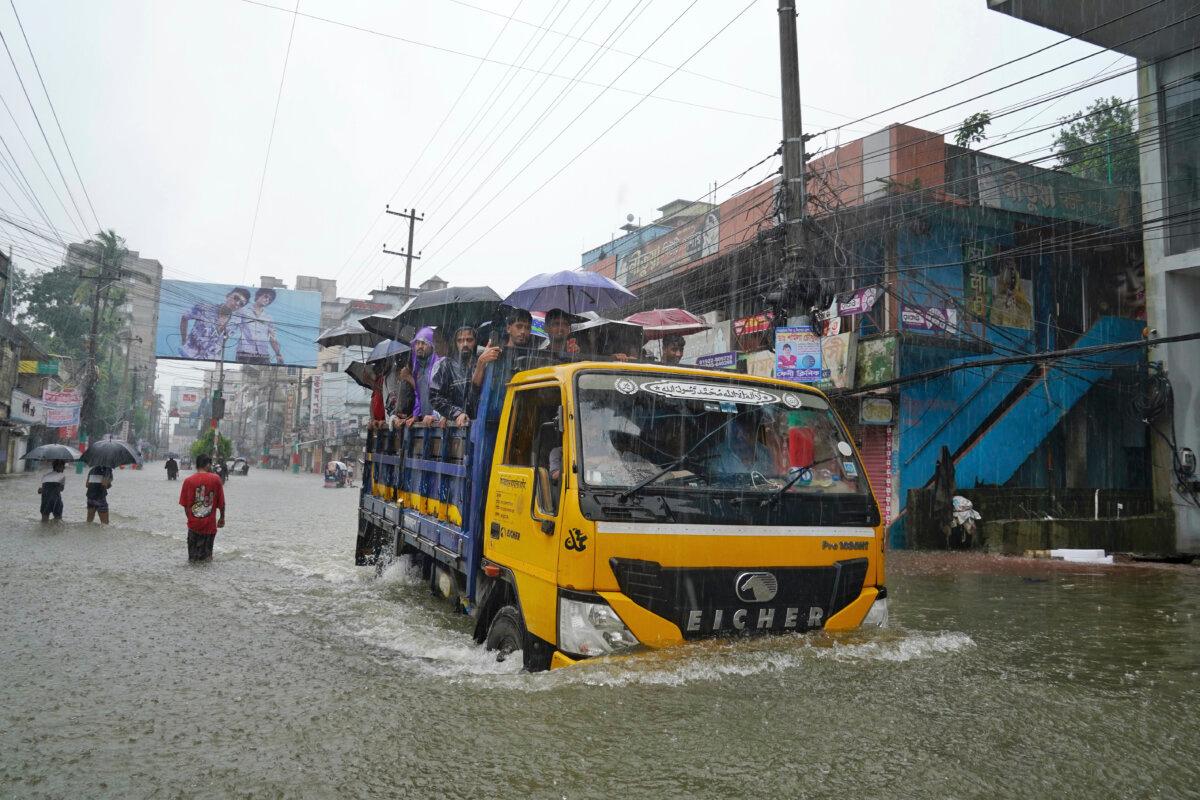 People ride on the back of a truck as they navigate a flooded street following incessant rains in Feni, a coastal district in southeast Bangladesh bordering the Indian Tripura state, on Aug. 22, 2024. (AP Photo)