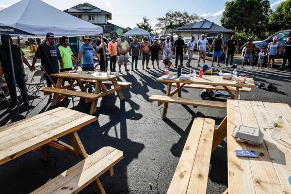 Lahaina, Maui, Monday, August 14, 2023-Lahaina residents and volunteers join hands in prayer at an aid distribution center on Wahinoho Way. (Robert Gauthier/Los Angeles Times)