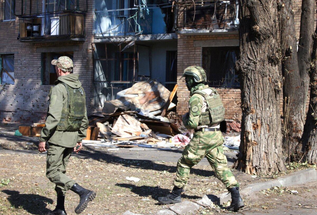 Local volunteers walk past a building damaged by Ukrainian strikes in Kursk, Russia, on Aug. 16, 2024. (Tatyana Makeyeva/AFP via Getty Images)