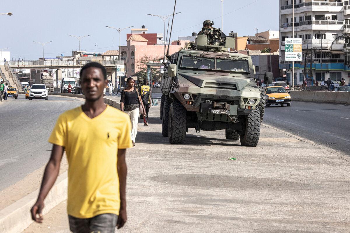 People walk past members of the Senegalese Armed Forces patrolling the streets following violent protests in Dakar, Senegal, on June 2, 2023. (John Wessels/AFP via Getty Images)