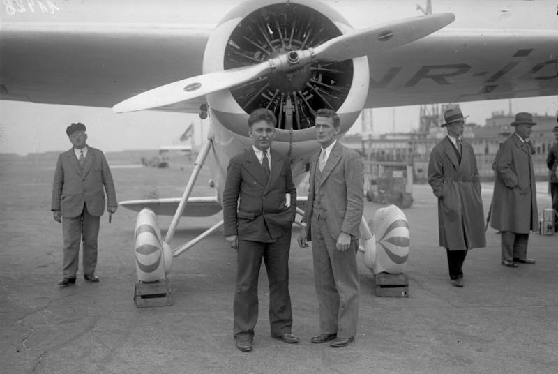 Wiley Post (L, Center) and Harold Gatty stop for a break in Berlin before taking off on the next leg of their worldwide flight. Next stop: Moscow. (<a href="https://en.wikipedia.org/wiki/User:ReneeWrites">Bundesarchiv, Bild 102-11928</a>/<a href="https://creativecommons.org/licenses/by-sa/3.0/de/deed.en">CC BY-SA 3.0</a>)
