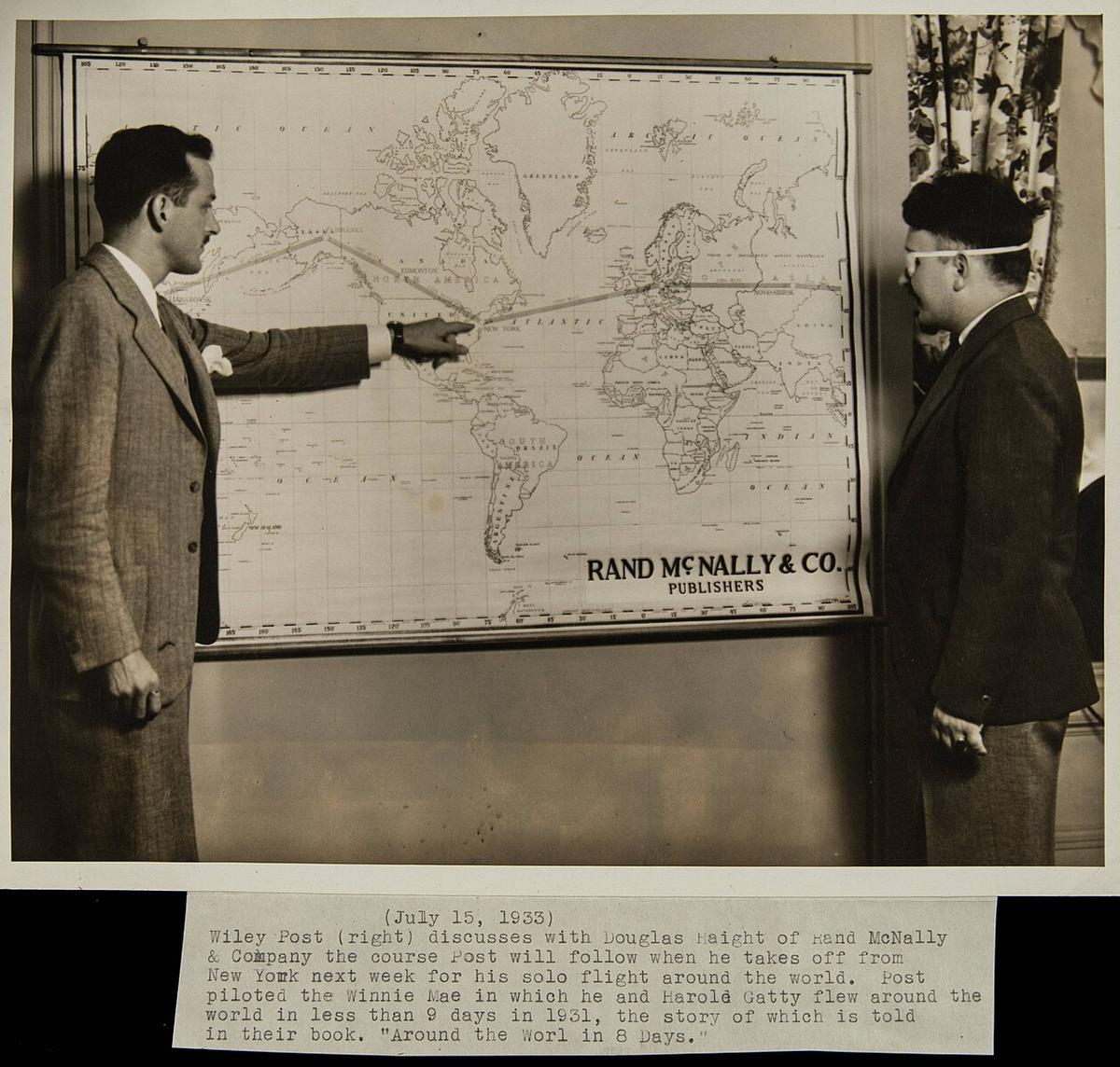Wiley Post (R) discusses his route around the world with Douglas Haight, a representative from the map supplier Rand McNally & Company. (Public Domain)