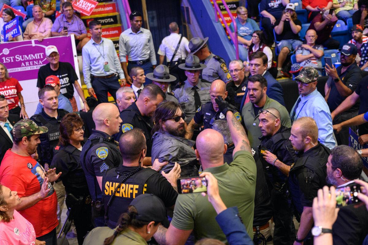 A man is apprehended by security and police after jumping onto the media platform at a campaign rally for Republican presidential nominee, former U.S. President Donald Trump at the 1st Summit Arena in Johnstown, Pa., on Aug. 30, 2024. (Justin Merriman/Getty Images)