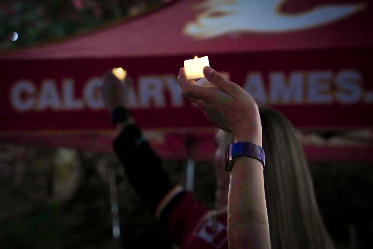 An attendee holds an electric candle at the vigil honouring former Calgary Flames star Johnny Gaudreau and his brother Matthew outside the Scotiabank Saddledome in Calgary on Sept. 4, 2024. (Carolina Avendano/The Epoch Times)