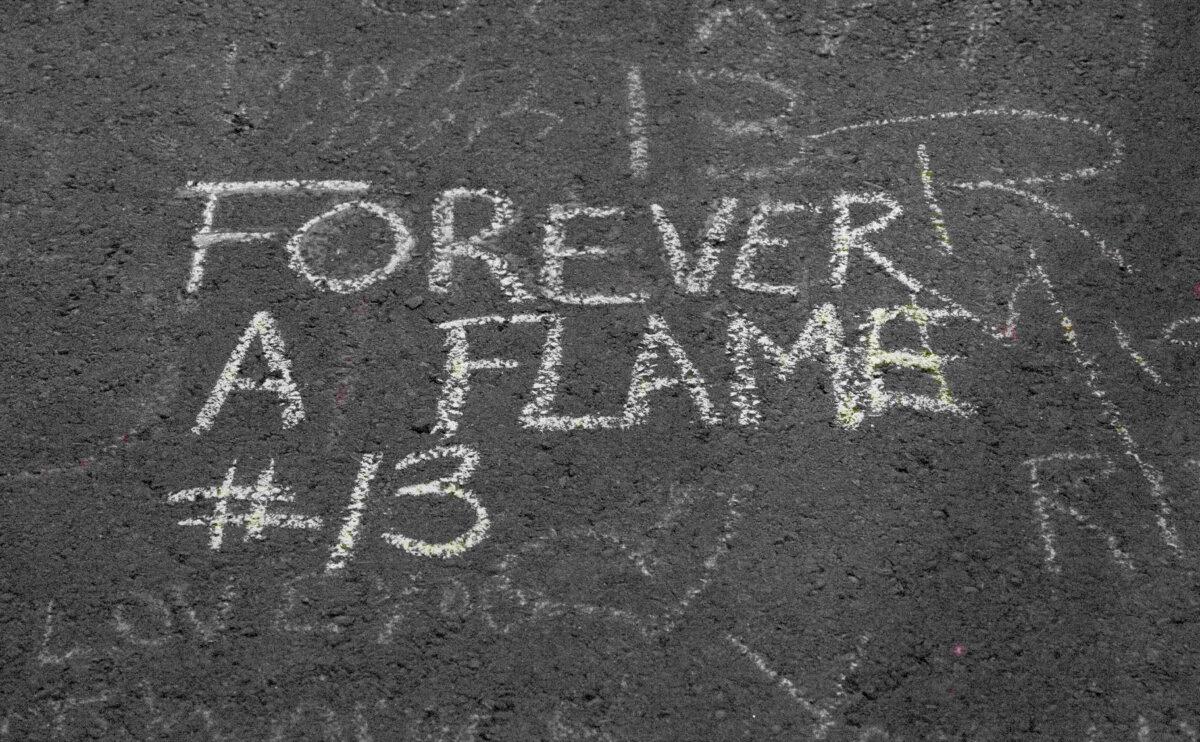Message written by Paige Liebreich and Kyra MacDonald on the pavement next to the Saddledome arena after a candlelight vigil honouring former Calgary Flames star Johnny Gaudreau and his brother Matthew in Calgary on Sept. 4, 2024. (Carolina Avendano/The Epoch Times)