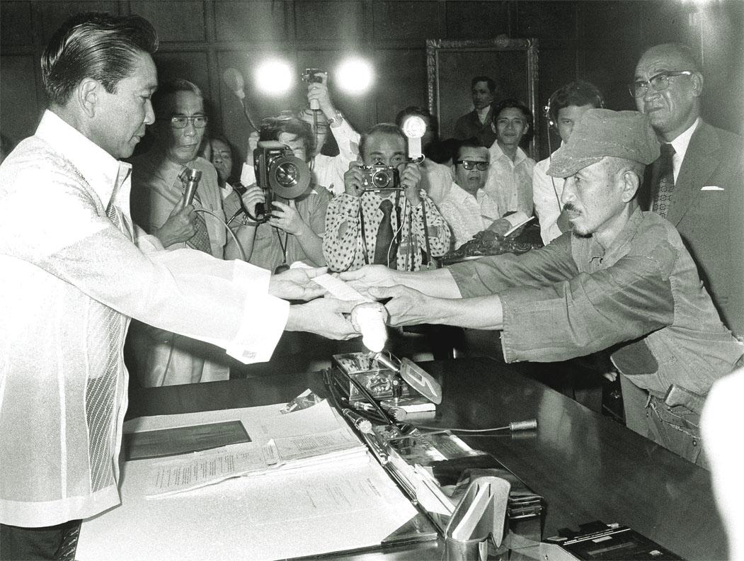 Japanese straggler Hiroo Onoda (R) surrenders his samurai sword to Philippine President Ferdinand E. Marcos (L), at the presidential palace in Manila, March 11, 1974. (Public Domain)