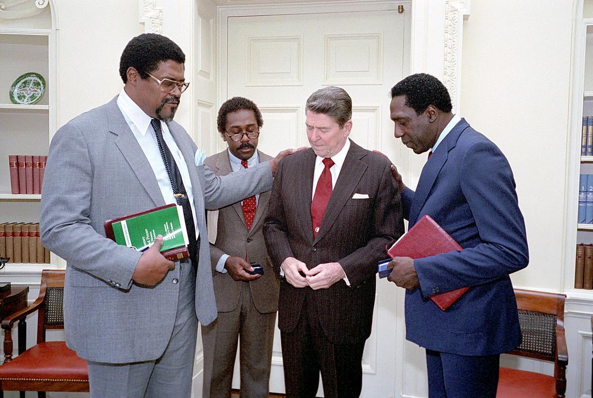 (L–R) On March 1, 1984, Roosevelt (Rosey) Grier, Demond Wilson, President Ronald Reagan, and Meadowlark Lemon join in prayer after a meeting about voluntary school prayer. (Public Domain)