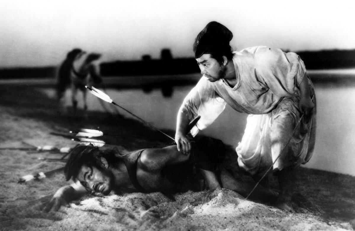 A police officer (Daisuke Kato, R) finds Tajomaru (Toshiro Mifune) wounded with arrows in his back, in “Rashomon.” (Criterion Collection)