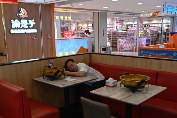 A man rests at a restaurant inside a shopping mall in Beijing on Aug. 14, 2024. (Pedro Pardo/AFP)