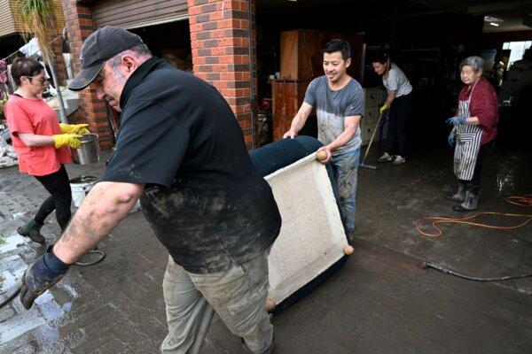 People carry household items from a property affected by floods in Melbourne, Australia, on Oct, 15, 2022. (William West/AFP via Getty Images)