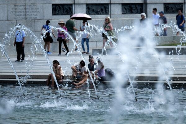 People rest their feet in a reflecting pool at the World War II Memorial on the National Mall in Washington, D.C., on Aug. 28, 2024. (Brendan Smialowski/AFP/Getty Images/TNS)