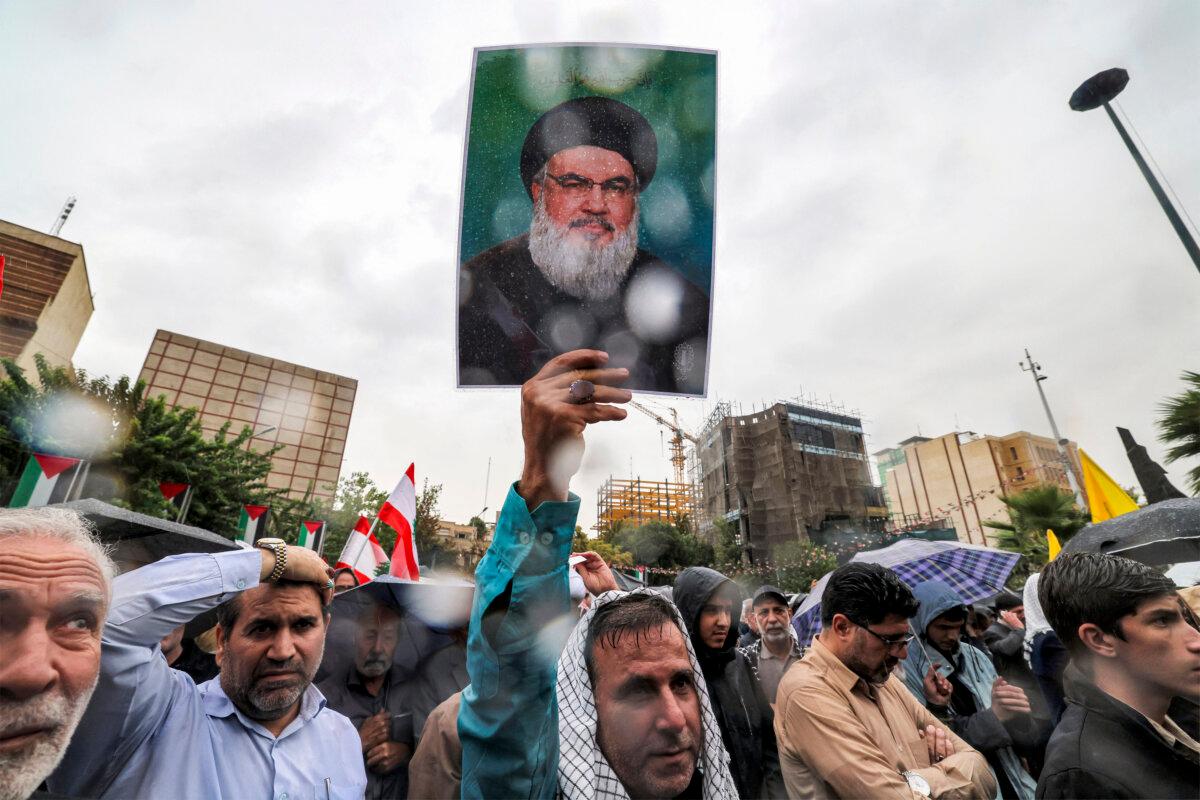 A demonstrator stands in the rain holding up a picture of late Lebanese Hezbollah leader Hassan Nasrallah during an anti-Israel protest in Tehran's Palestine Square, Iran, on Sept. 28, 2024. (Atta Kenare/AFP via Getty Images)