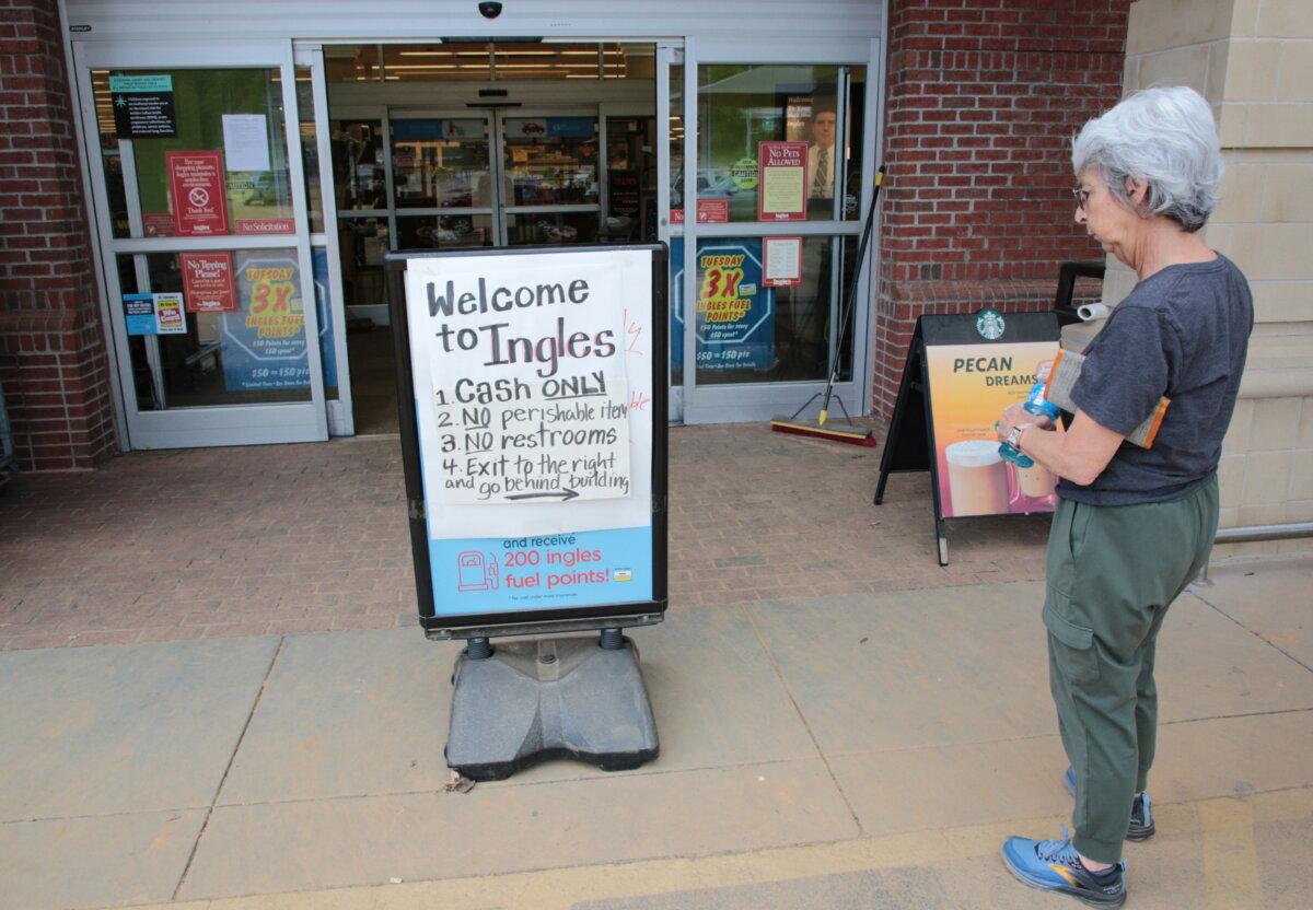 A shopper stops at the entrance of the Ingles supermarket to read about what's available, in Swannanoa, N.C., on Oct. 2, 2024. (Richard Moore/The Epoch Times)