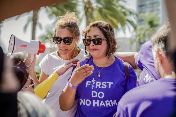 Erin Friday (L) comforts Abigail Martinez (R), the mother of a transgender teen who committed suicide, while transgender activists block TV cameras from capturing her story, in Anaheim, Calif., on Oct. 8, 2022. (John Fredricks/The Epoch Times)