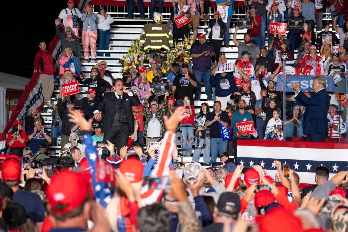 Christopher Macchio, lyric tenor, performs onstage as former President Donald J. Trump claps at a rally at Butler Farm Show in Butler, Pa., on Oct. 5, 2024. (Samira Bouaou/The Epoch Times)