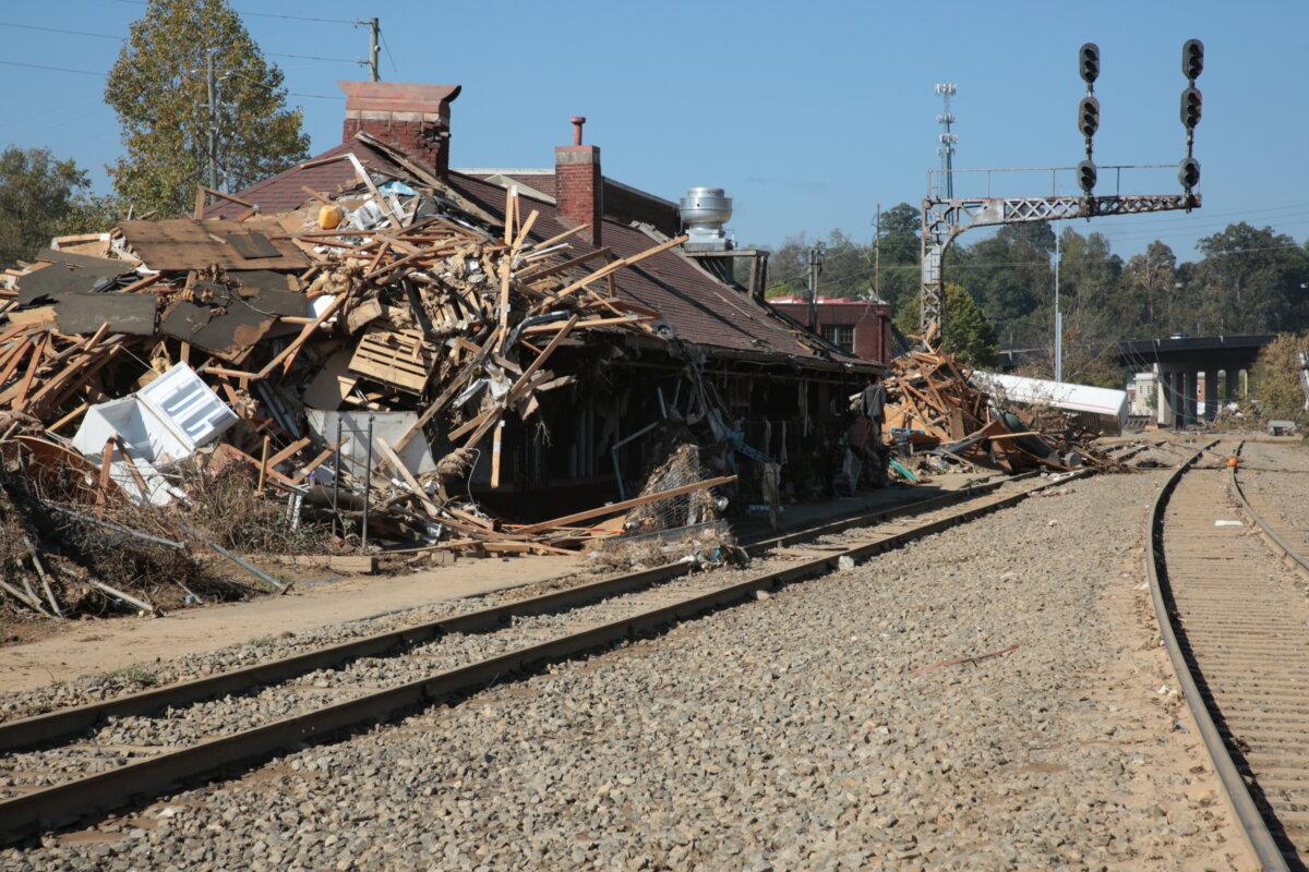 Flood wreckage stacked against a railway building in Biltmore Village, N.C., on Oct. 4, 2024. (Richard Moore/The Epoch Times)