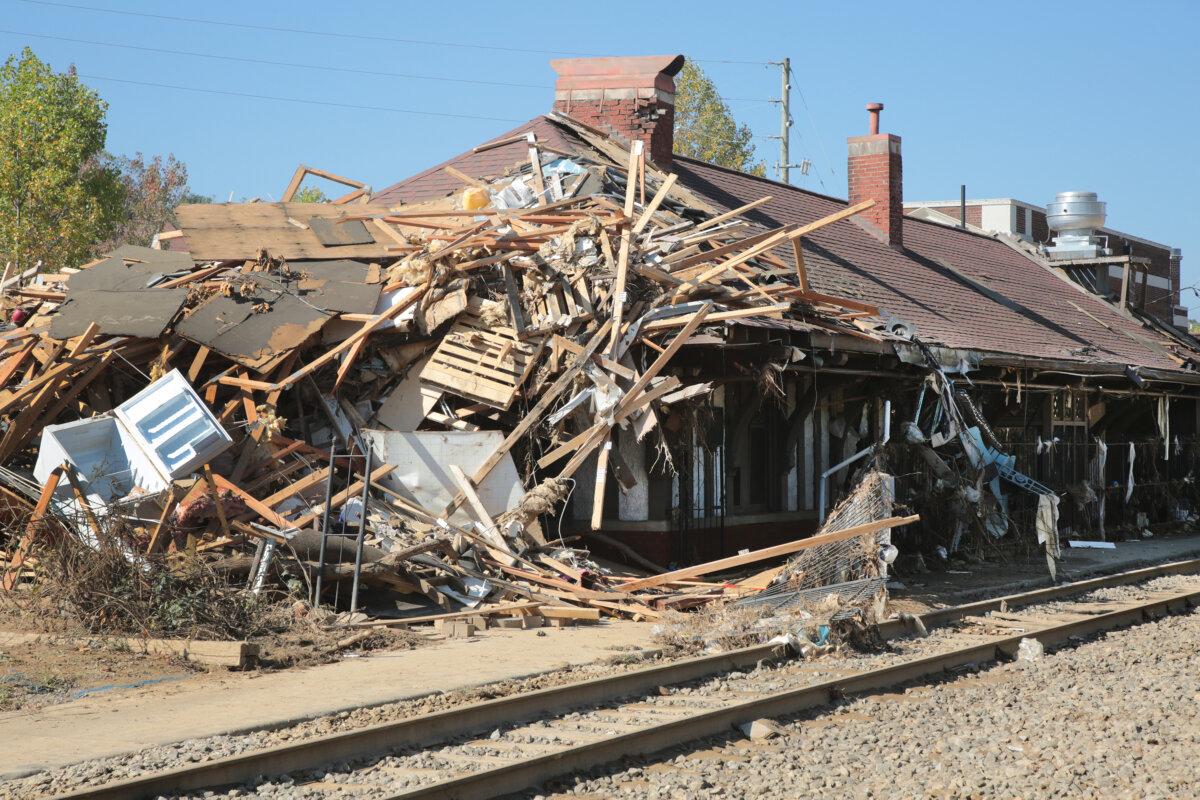Debris is piled up against a railway building in Biltmore Village, Asheville, N.C., on Oct 4, 2024. (Richard Moore/The Epoch Times)