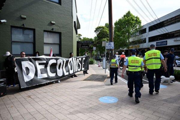 Demonstrators hold a banner saying "decolonise" as they wait for the arrival of Britain's King Charles III and Queen Camilla to attend a Sunday morning service at St Thomas' Anglican Church in Sydney, Australia on Oct. 20, 2024. (Dean Lewins-Pool/Getty Images)
